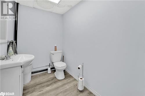 Bathroom featuring toilet, vanity, wood-type flooring, and a baseboard heating unit - 8876 County Road 56, Utopia, ON 