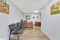 Home office with light wood-type flooring and a paneled ceiling - 