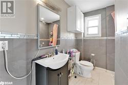 Bathroom with a shower with curtain, vanity, toilet, and tile walls - 