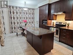 Kitchen featuring hanging light fixtures, light tile patterned floors, stainless steel appliances, and dark stone counters - 