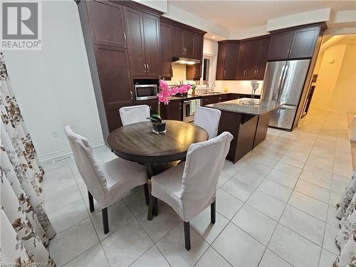 Kitchen featuring a center island, sink, stainless steel appliances, dark stone countertops, and light tile patterned floors - 218 Gravel Ridge Trail, Kitchener, ON - Indoor Photo Showing Dining Room