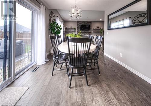 Dining room featuring hardwood / wood-style floors, an inviting chandelier, and a stone fireplace - 66 Lock Street, Innerkip, ON - Indoor Photo Showing Dining Room