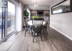 Dining room featuring hardwood / wood-style floors, an inviting chandelier, and a stone fireplace - 