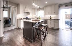 Kitchen featuring white cabinets, washer / clothes dryer, a kitchen island, and premium range hood - 