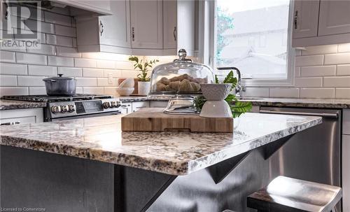 Kitchen with custom exhaust hood, stove, stainless steel dishwasher, light stone countertops, and tasteful backsplash - 66 Lock Street, Innerkip, ON - Indoor Photo Showing Kitchen With Upgraded Kitchen