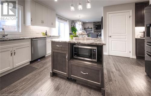 Kitchen featuring sink, light stone countertops, appliances with stainless steel finishes, dark hardwood / wood-style flooring, and white cabinetry - 66 Lock Street, Innerkip, ON - Indoor Photo Showing Kitchen With Upgraded Kitchen