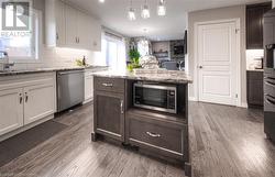 Kitchen featuring sink, light stone countertops, appliances with stainless steel finishes, dark hardwood / wood-style flooring, and white cabinetry - 