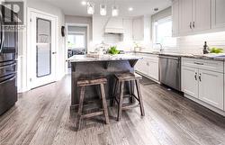 Kitchen with hanging light fixtures, light stone counters, stainless steel dishwasher, independent washer and dryer, and premium range hood - 