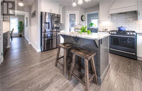 Kitchen with decorative backsplash, appliances with stainless steel finishes, custom exhaust hood, white cabinets, and a kitchen island - 66 Lock Street, Innerkip, ON - Indoor Photo Showing Kitchen With Stainless Steel Kitchen With Upgraded Kitchen