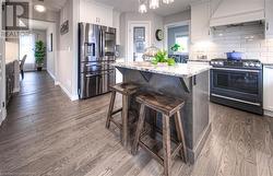 Kitchen with decorative backsplash, appliances with stainless steel finishes, custom exhaust hood, white cabinets, and a kitchen island - 