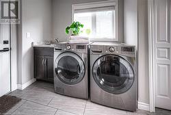 Laundry room featuring cabinets, washing machine and dryer, light tile patterned floors, and sink - 