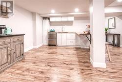 Bar featuring white cabinets, sink, and light hardwood / wood-style flooring - 