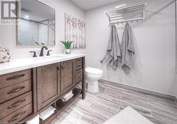 Bathroom with vanity, toilet, and tiled shower - 