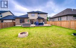 Rear view of property with a lawn, an outdoor fire pit, and a wooden deck - 