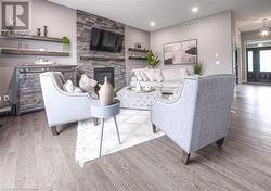 Living room featuring a stone fireplace and light hardwood / wood-style floors - 