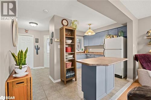 Kitchen featuring stainless steel dishwasher, light tile patterned floors, decorative light fixtures, white fridge, and a kitchen island - 17 Emslie Street, Halton, ON - Indoor Photo Showing Kitchen