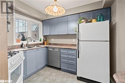 Kitchen featuring pendant lighting, white appliances, sink, and light tile patterned floors - 17 Emslie Street, Halton, ON - Indoor Photo Showing Kitchen With Double Sink