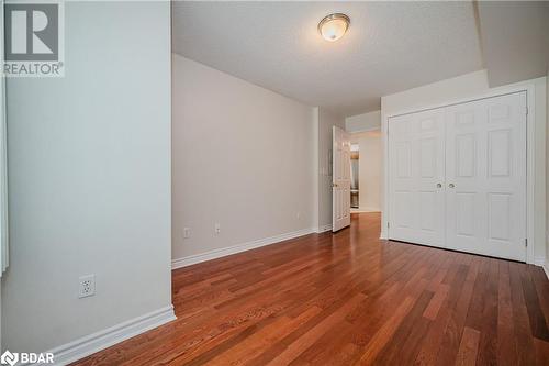 Unfurnished bedroom featuring a textured ceiling, hardwood / wood-style flooring, and a closet - 2300 Parkhaven Boulevard Unit# 103, Oakville, ON - Indoor Photo Showing Other Room