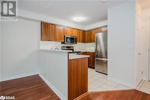 Kitchen with light wood-type flooring, kitchen peninsula, and stainless steel appliances - 2300 Parkhaven Boulevard Unit# 103, Oakville, ON - Indoor Photo Showing Kitchen