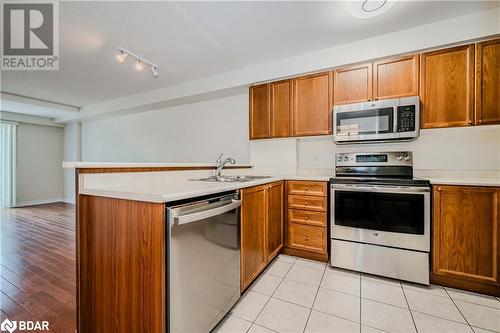 Kitchen featuring kitchen peninsula, appliances with stainless steel finishes, light tile patterned floors, and sink - 2300 Parkhaven Boulevard Unit# 103, Oakville, ON - Indoor Photo Showing Kitchen