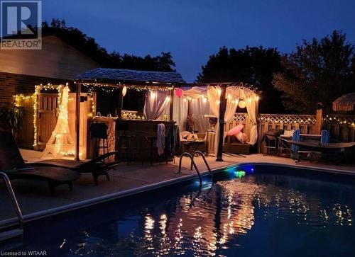 View of pool in the evening with a patio bar and a patio area - 11 Golden Place, Ingersoll, ON - Outdoor