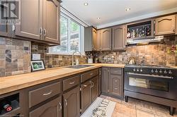 Kitchen featuring sink, decorative backsplash, high end stove, range hood, and butcher block counters - 