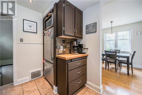 Kitchen with wooden counters, decorative backsplash, stainless steel fridge, decorative light fixtures, and dark brown cabinetry - 48 Dane Street, Kitchener, ON - Indoor