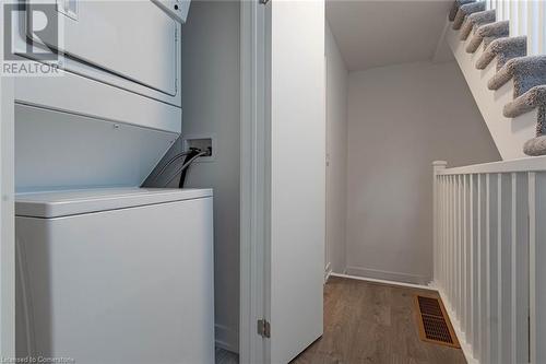 Clothes washing area featuring stacked washer and dryer and light hardwood / wood-style flooring - 1121 Cooke Boulevard Unit# 7, Burlington, ON - Indoor Photo Showing Laundry Room