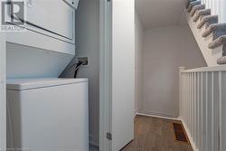 Clothes washing area featuring stacked washer and dryer and light hardwood / wood-style flooring - 