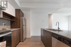 Kitchen featuring ventilation hood, stainless steel appliances, sink, light hardwood / wood-style floors, and white cabinetry - 