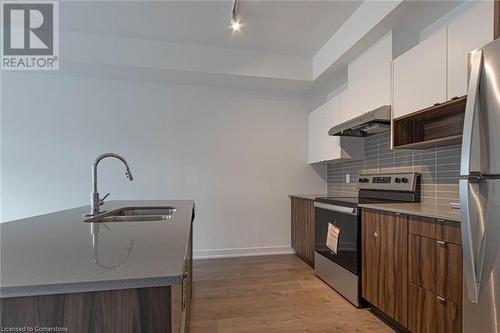 Kitchen featuring backsplash, stainless steel appliances, sink, white cabinets, and light hardwood / wood-style floors - 1121 Cooke Boulevard Unit# 7, Burlington, ON - Indoor Photo Showing Kitchen With Double Sink