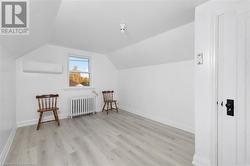 Bonus room featuring radiator heating unit, vaulted ceiling, light hardwood / wood-style flooring, and an AC wall unit - 