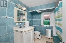 Bathroom with vanity, radiator, a shower with curtain, tile patterned flooring, and tile walls - 