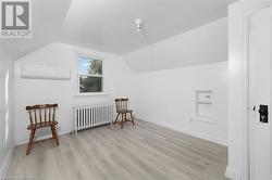 Bonus room featuring radiator, built in shelves, a wall mounted AC, and lofted ceiling - 