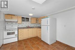 Kitchen with backsplash, tile patterned floors, white appliances, sink, and light brown cabinets - 