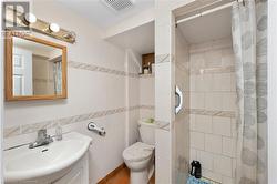 Bathroom with a shower with curtain, toilet, tile walls, and sink - 