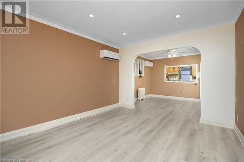 Empty room with ornamental molding, a wall mounted AC, ceiling fan, light hardwood / wood-style flooring, and radiator heating unit - 349 Kipling Avenue, Etobicoke, ON - Indoor Photo Showing Other Room