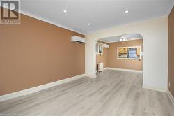 Empty room with ornamental molding, a wall mounted AC, ceiling fan, light hardwood / wood-style flooring, and radiator heating unit - 