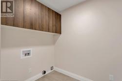 Clothes washing area featuring hookup for a washing machine, light tile patterned floors, and cabinets - 