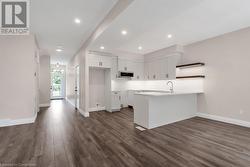 Kitchen featuring dark hardwood / wood-style floors, sink, white cabinetry, and kitchen peninsula - 