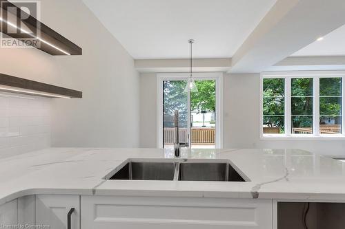 Kitchen with decorative backsplash, light stone counters, white cabinets, and pendant lighting - 3C Balsam Street, Innerkip, ON - Indoor Photo Showing Kitchen