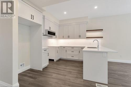 Kitchen featuring white cabinetry, sink, dark wood-type flooring, decorative backsplash, and a kitchen island - 3C Balsam Street, Innerkip, ON - Indoor Photo Showing Kitchen