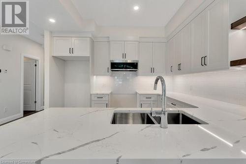 Kitchen featuring backsplash, light stone countertops, sink, and white cabinets - 3C Balsam Street, Innerkip, ON - Indoor Photo Showing Kitchen With Double Sink