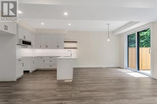 Kitchen featuring pendant lighting, a center island with sink, sink, white cabinetry, and wood-type flooring - 3C Balsam Street, Innerkip, ON - Indoor Photo Showing Kitchen