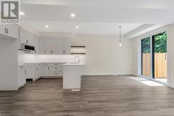 Kitchen featuring pendant lighting, a center island with sink, sink, white cabinetry, and wood-type flooring - 