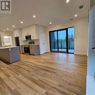 Kitchen with stove, white cabinets, light hardwood / wood-style floors, and sink - 