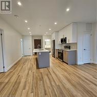 Kitchen with a center island with sink, white cabinets, sink, light hardwood / wood-style floors, and range - 