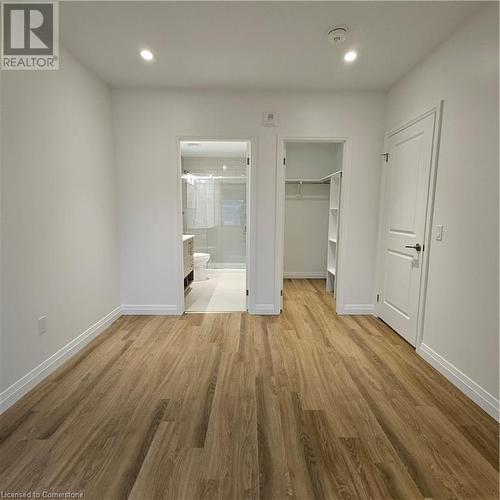 Unfurnished bedroom with light wood-type flooring, ensuite bath, a spacious closet, and a closet - 525 New Dundee Road Unit# 602, Kitchener, ON - Indoor Photo Showing Other Room