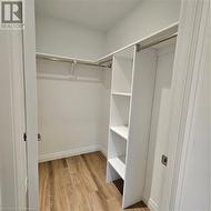 Spacious closet with light hardwood / wood-style floors - 