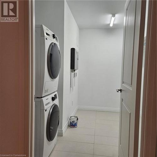 Washroom featuring light tile patterned floors and stacked washer / dryer - 525 New Dundee Road Unit# 602, Kitchener, ON - Indoor Photo Showing Laundry Room